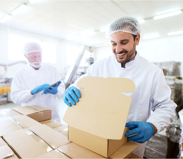 Two gowned technicians packing finished cartons on a production line