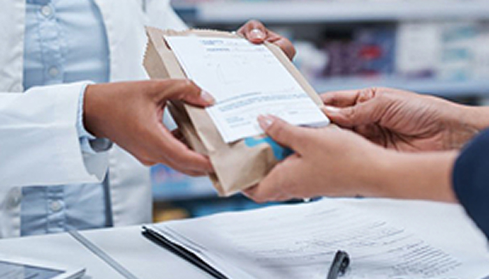 A pharmacist handing a filled prescription across the counter